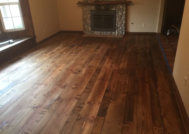 Dark stained wood floor in a living room with a stone fireplace