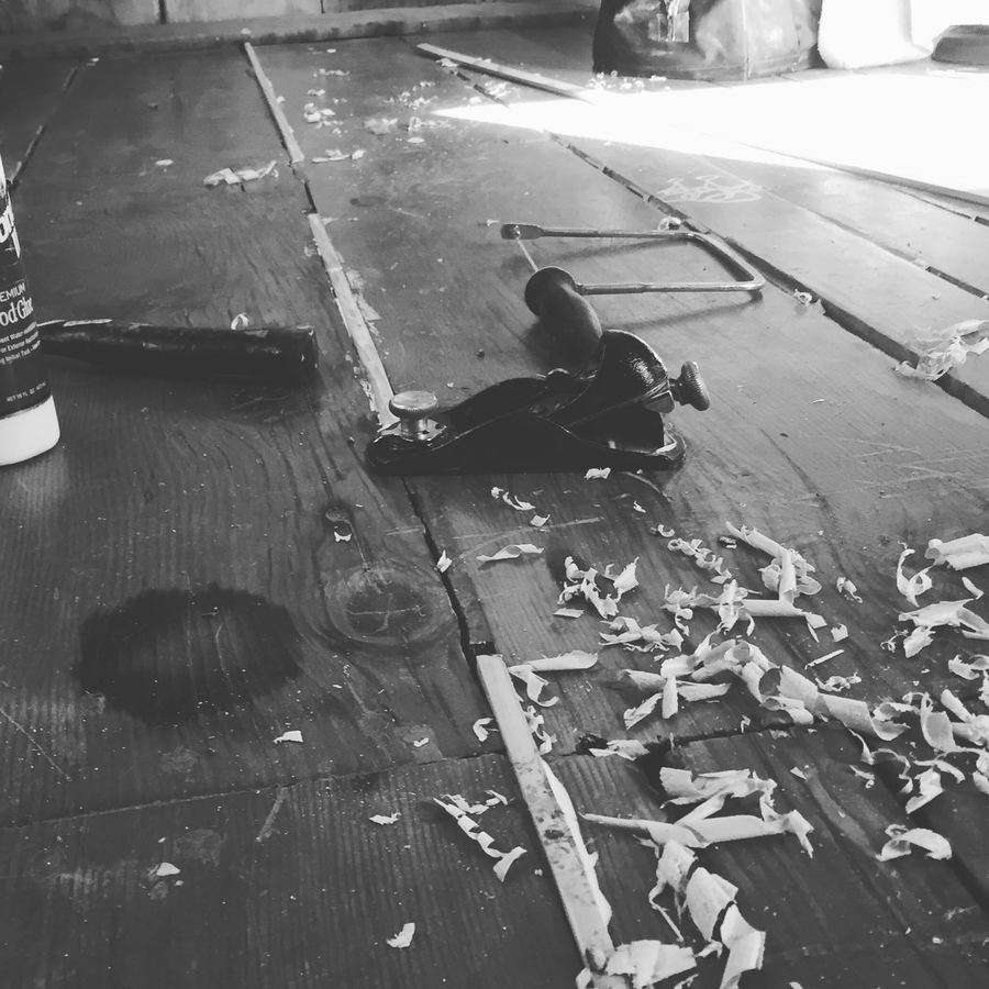 Black and white photo of a floor mid-repair with wood glue and shavings